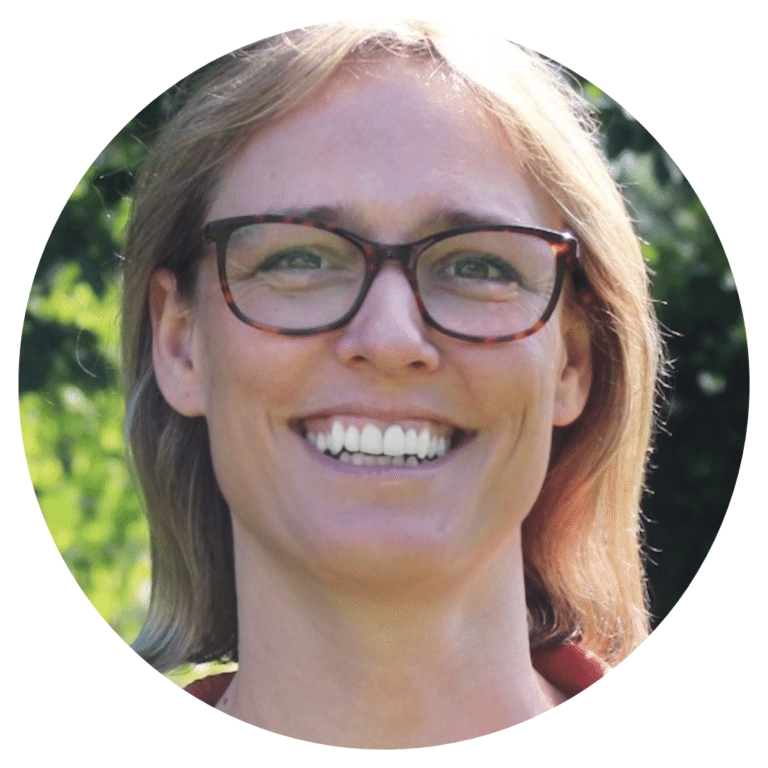 A headshot photo of a blond woman in glasses smiling