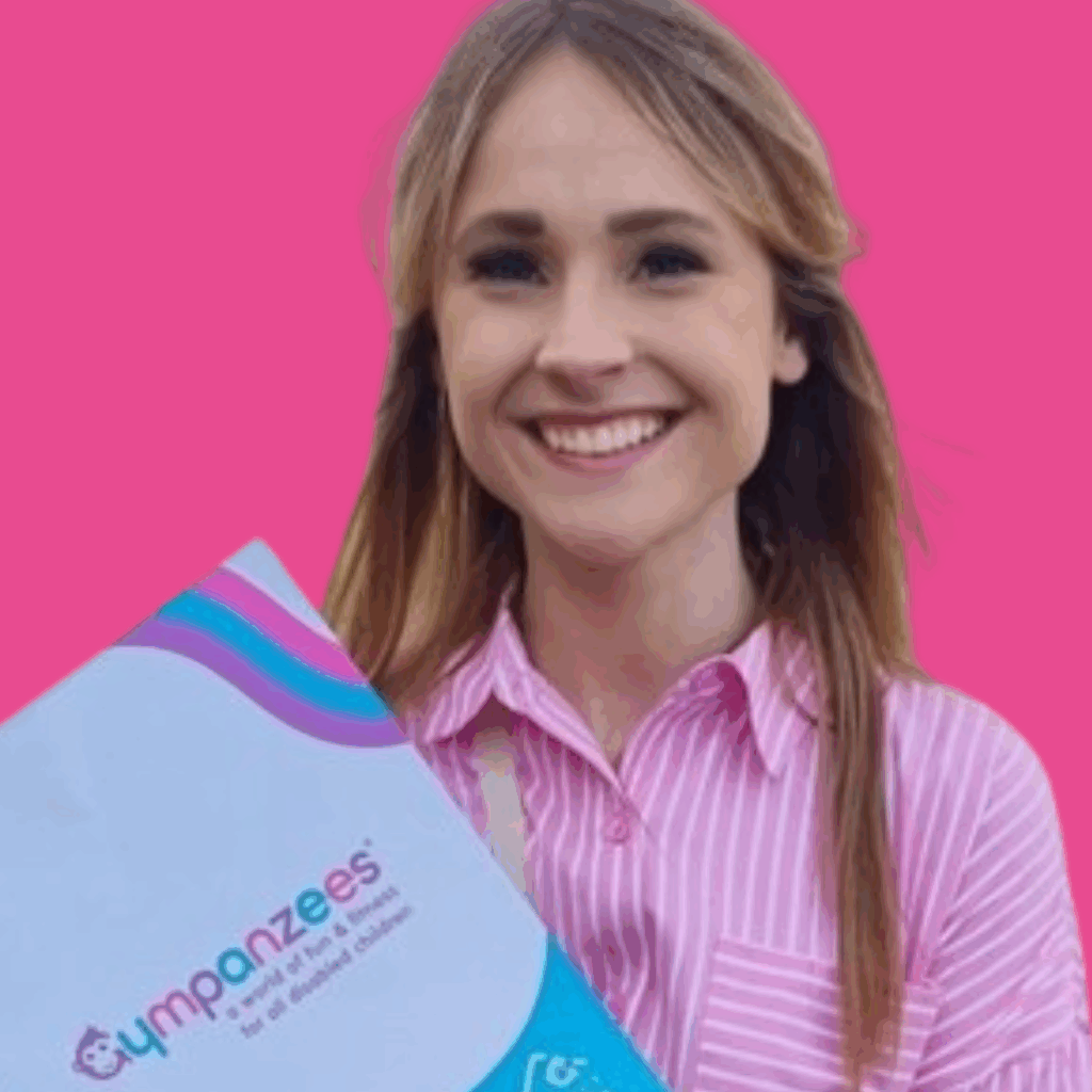 The image is of a woman in a pink blouse, with long, light hair, holding a branded gympanzees brochure, from the shoulders up, on a bright background smiling into the camera.