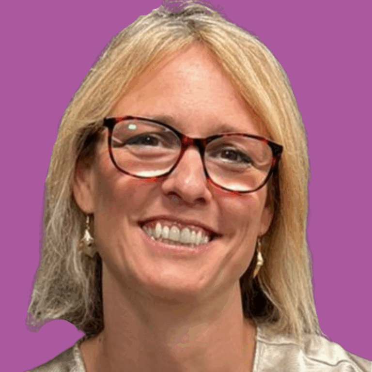 The image is of a lady from the shoulders up, with short light hair, dangly earrings and glasses smiling into the camera.