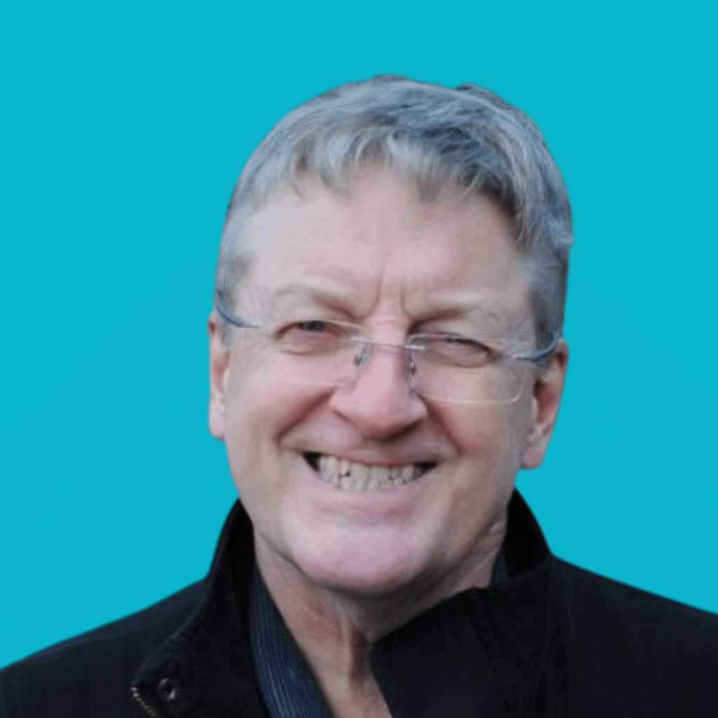 The image of a man from the shoulders up in a t-shirt, smiling into the camera on a bright background.