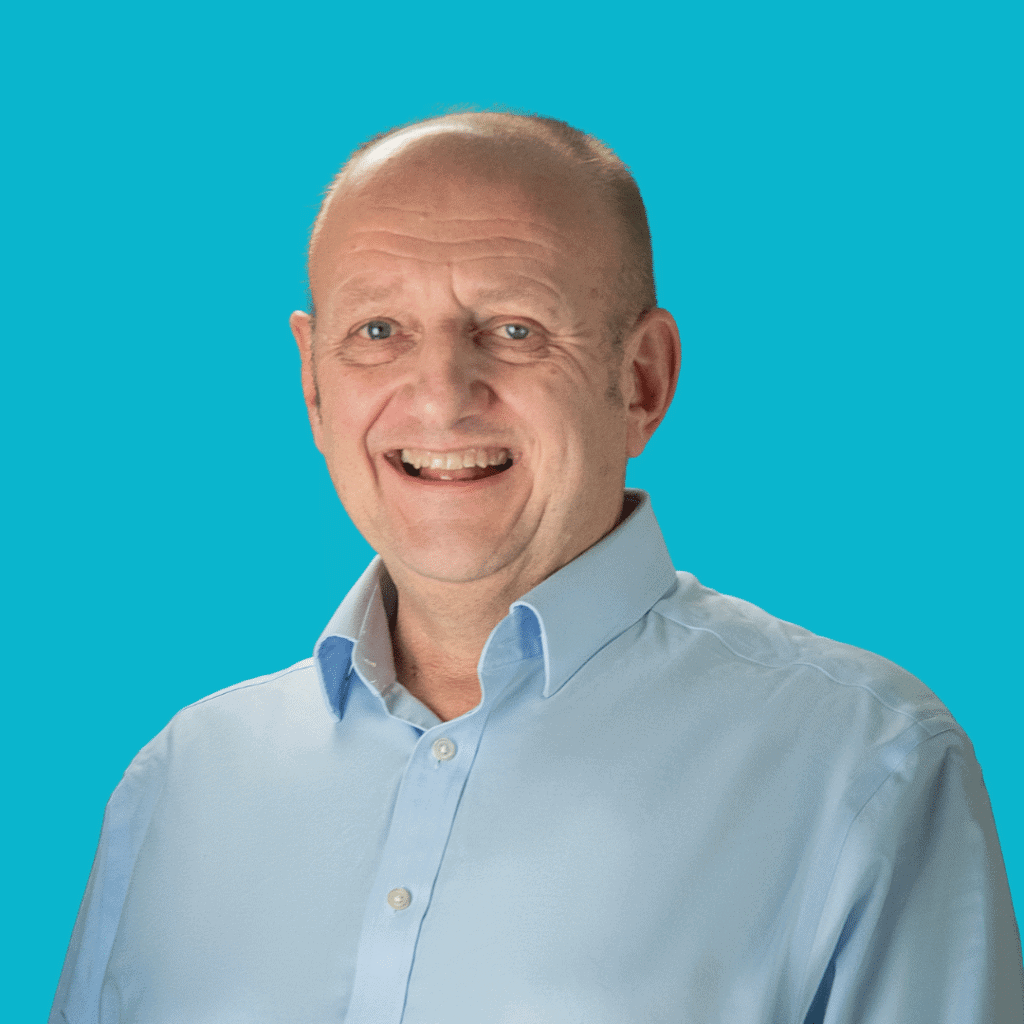 The image is of a man with a shaved head, from the shoulders up in a shirt, on a bright background.