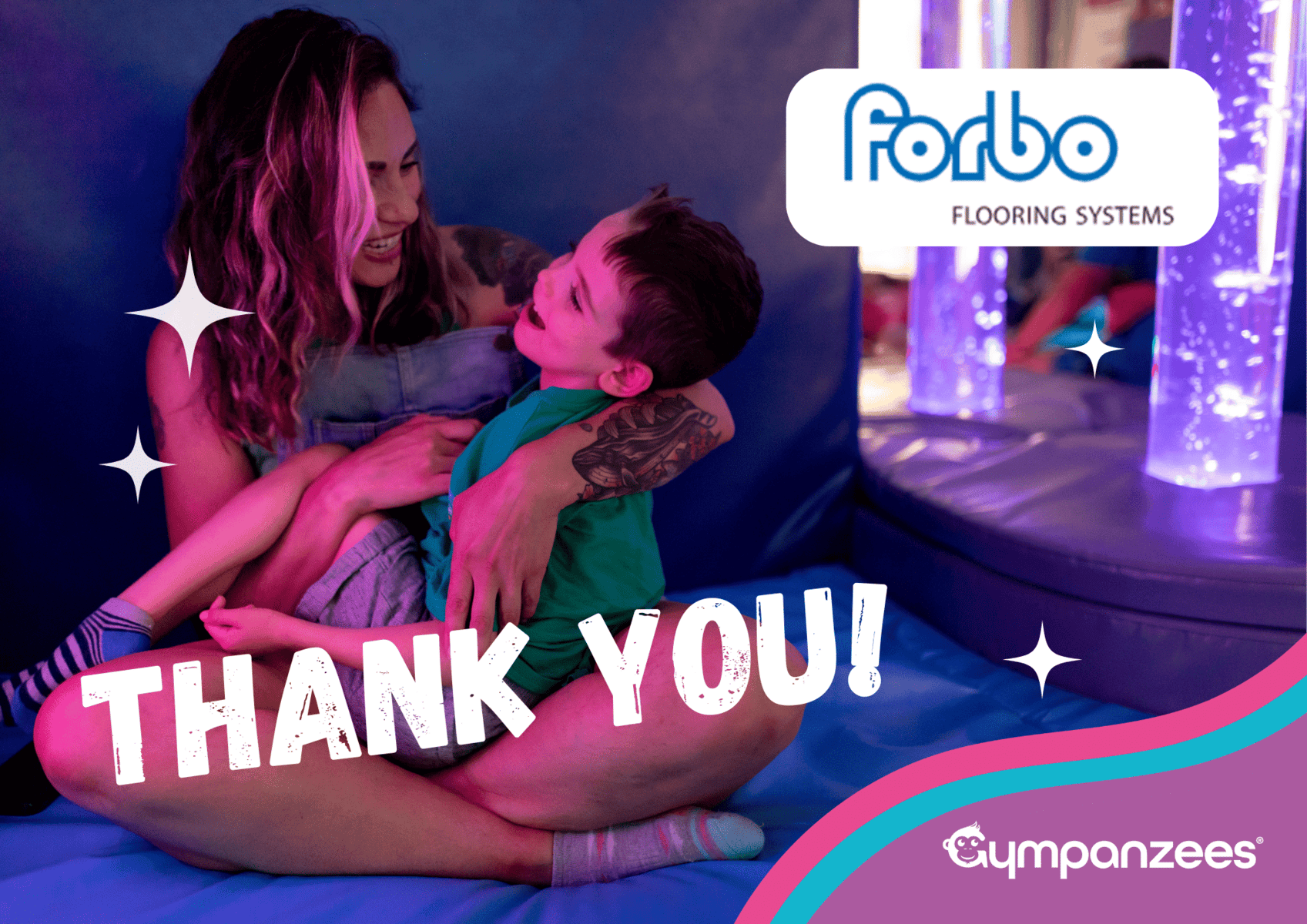 An adult sitting on a soft play mat holding a child on their lap, both smiling and looking at each other in a sensory room with colourful lights and bubble tubes. The image includes the text “Thank you!!” and a Forbo Flooring Systems logo, alongside Gympanzees branding.