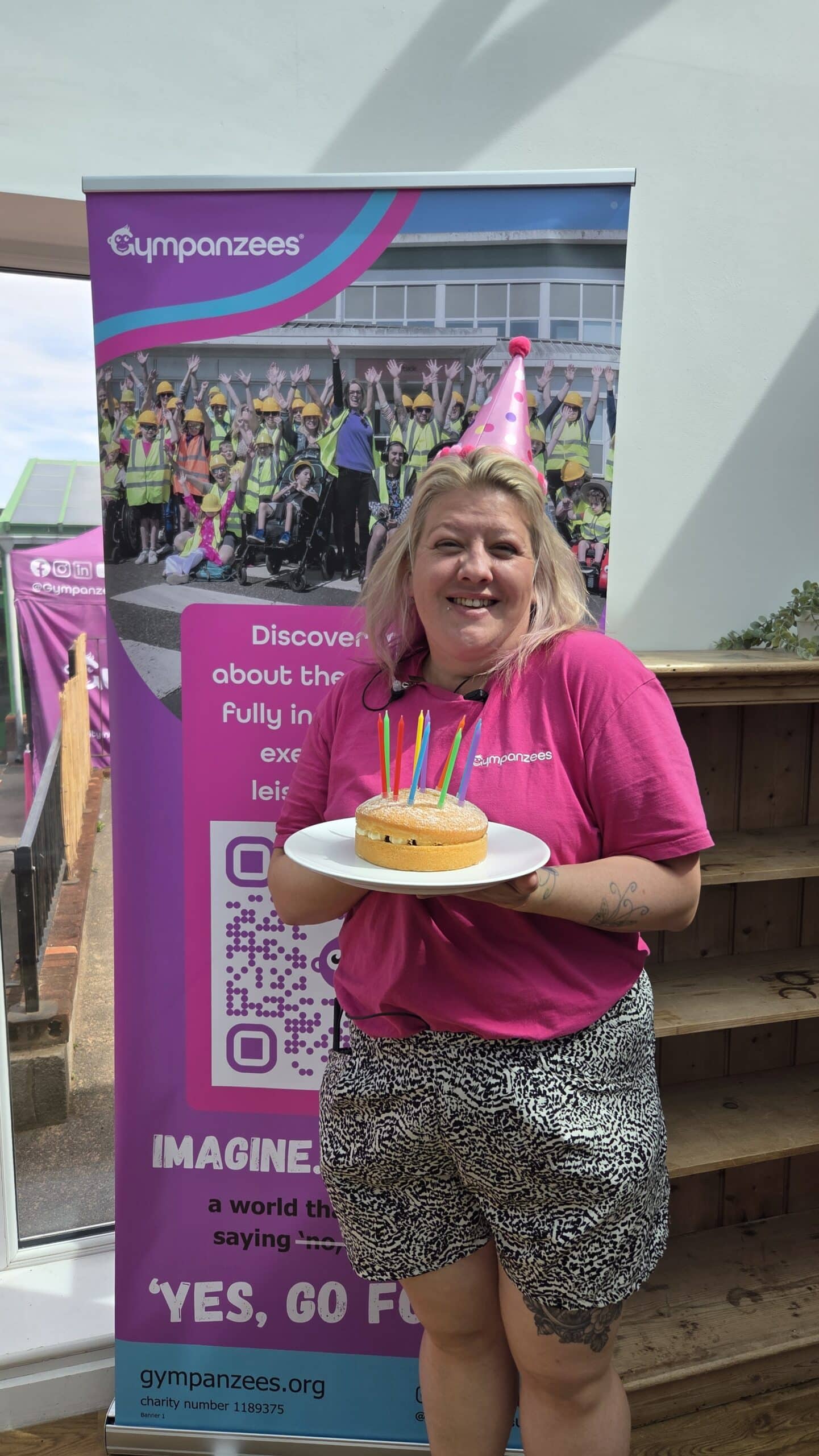 Fran at Gympanzees Pop Up holding a cake and wearing a party hat