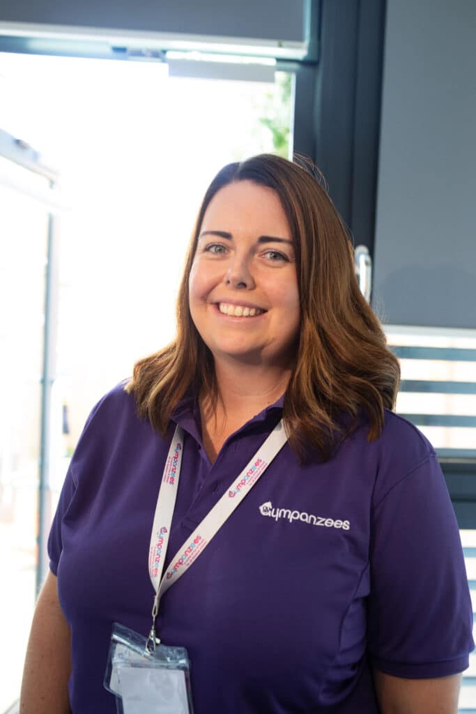 a photo of a smiling woman in a purple Gympanzees top with lanyard