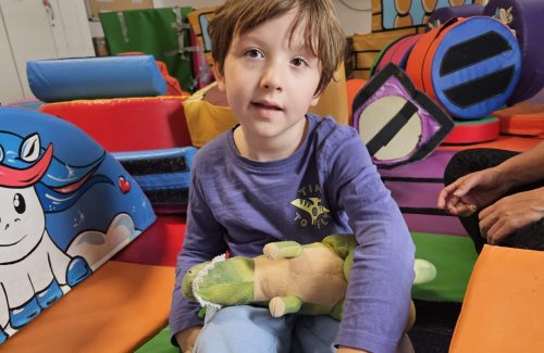 Young child sitting in a colourful softplay room