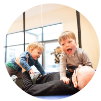 The image is of toy young boys smilling and laughing with their relativ led down on a large trampoline.