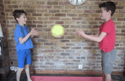 The image is of two young boys throwing a ball to each other.